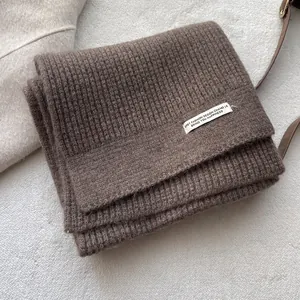 Detailansicht des dicken braunen Rippstrickschals aus Wolle mit weißem Textiletikett