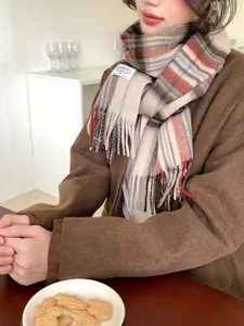 Detail of wool plaid scarf with fringes and minimalist brand label on fabric