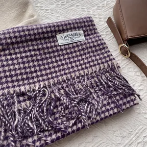 Detail of wool houndstooth scarf in purple and beige with fringe and branded woven label