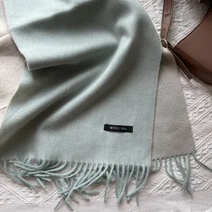 Close-up of dual-tone wool scarf featuring soft fringe and 100% pure wool label