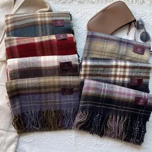 Close-up of thick plaid scarves with fringes in various colors and soft wool texture