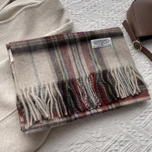 Detail view of the soft plaid scarf with fringe and a rectangular white brand label