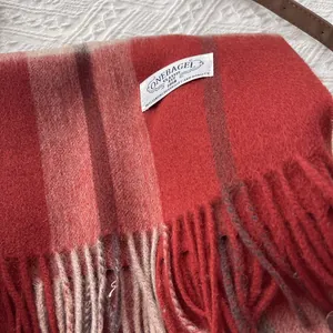 Detailed close-up of hazelnut red checkered cashmere scarf with soft fringe and logo label