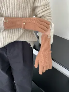 Detail of caramel wool knit gloves with cable pattern and branded woven label