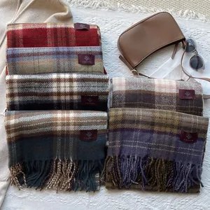 Flat lay of colorful vintage plaid scarves with tassels on waffle textured background