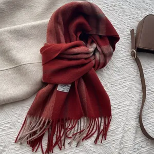 Detailed macro view of dark red plaid cashmere scarf with long fringe and brand label