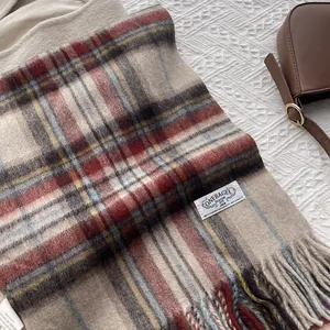 Detail of wool plaid scarf with red and beige check patterns and soft fringe tassels