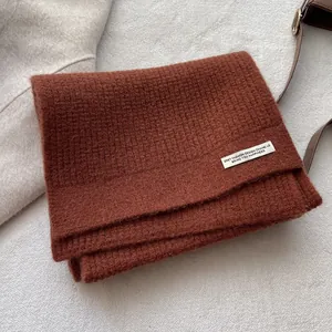 Detailstruktur des karamellfarbenen Waffelstrickschals aus Wolle mit weißem Aufnäher