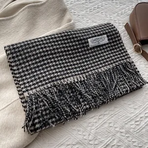 Detail of classic black and white houndstooth wool scarf with fringe and brand label