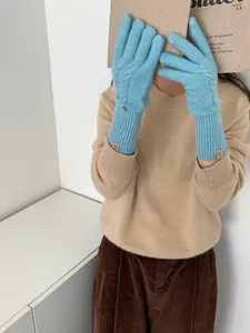 Detail of wool blend cable knit gloves in light blue with ribbed cuffs and logo patch