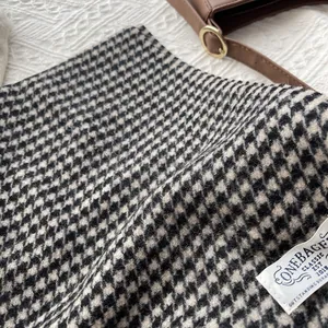 Close-up of premium black and white houndstooth wool scarf with brand woven label detail