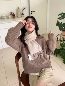 Detailansicht eines Wollschals mit Fransen und Markenetikett auf winterlichem Outfit