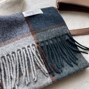 Detailaufnahme eines dicken Wollschals mit blau-braunem Karomuster und Fransenbesatz