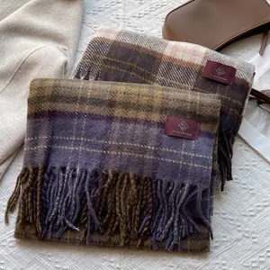 Detail of plaid scarves with fringe ends and woven brand labels on textured background