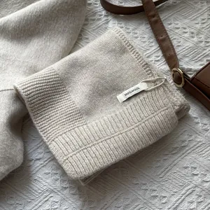 Detalle de bufanda de lana pura con etiqueta que muestra textura de punto beige