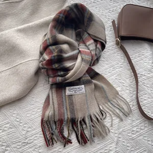 Close-up of beige plaid wool scarf with colorful fringe detail and brand label