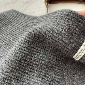 Detail von grauem Rippstrick-Gewebe mit dicker Textur und genähtem weißem Textiletikett