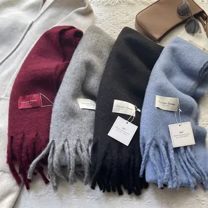 Flat lay of multiple colorful cashmere scarves with tassel edges and brand tags