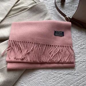 Detail of pink wool scarf with fringe and woven label for winter outfit styling