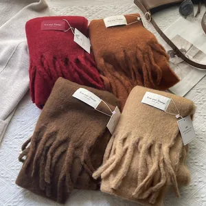 Close-up of wool-blend scarves with long tassels and premium 'Hand Made' woven labels