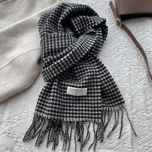 Detailed close-up of a classic houndstooth wool scarf featuring elegant fringe and brand tag
