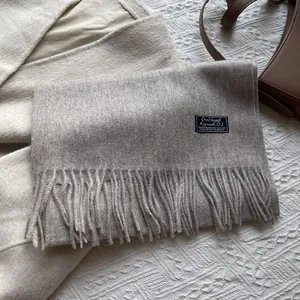Close-up of luxury grey wool scarf with long tassels and minimalist brand label
