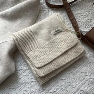 Detalle de bufanda de lana pura blanco crema mostrando tejido fino y etiqueta de material