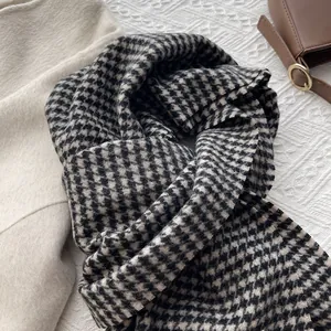 Flat lay of wool houndstooth scarf in black and beige styled with a winter coat