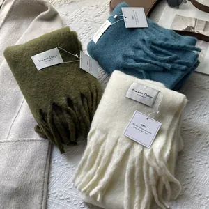Detail of wool scarves with tassels in olive green, lake blue, and cream white colors