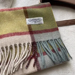 Detailaufnahme von dickem Wollschal mit buntem Karomuster, Fransen und gewebtem Markenetikett