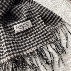 Detail of classic houndstooth wool scarf with fringe edges and premium woven label