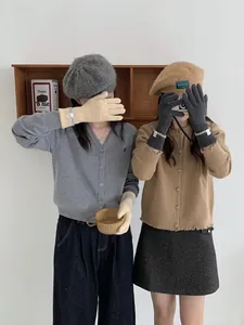 Gilet en maille grise et gants assortis portés avec une jupe à carreaux pour l'hiver