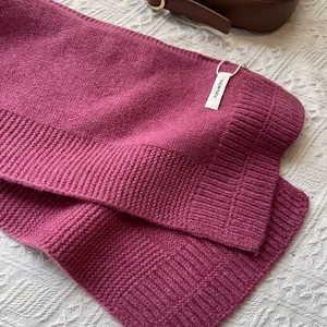 Detalle de bufanda de 100% lana rosa oscuro con bordes acanalados y etiqueta de lana