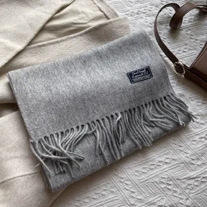 Detail of grey wool scarf featuring elegant tassel fringe and a classic woven label