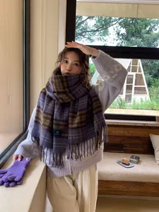 Detail of a thick purple plaid scarf with long fringe paired with a knit cardigan