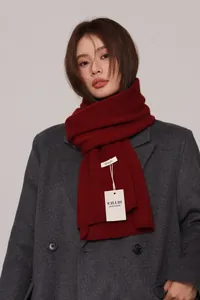 Detail of burgundy wool scarf with 100% wool label and hand made tag on grey coat