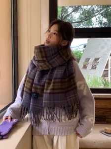 Close-up of thick checkered scarf with purple, green tassels and knit floral cardigan