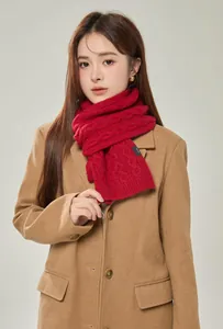 Detail of red wool scarf featuring thick cable knit texture and 100% wool quality label