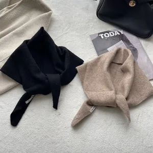 Écharpe triangle en maille de laine pour femme en noir et camel sur tapis en peluche