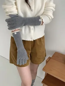 Détail de gants en cachemire tricotés gris avec petite étiquette smiley sur le poignet