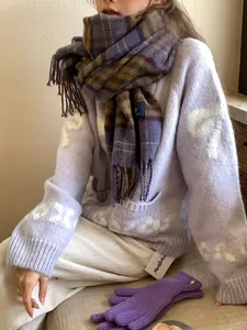 Detail of warm checkered tassel scarf with matching purple gloves and snowflake knit sweater