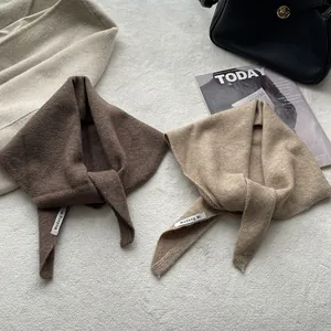 Texture détaillée d'un foulard triangulaire en maille de laine douce aux tons café