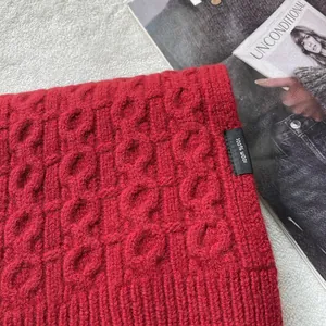 Macro shot of 100% pure wool red cable knit scarf texture and material care label