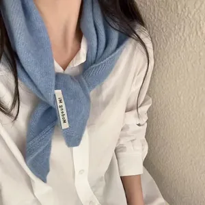 Gros plan d'une écharpe en maille bleu doux avec étiquette sur une chemise blanche