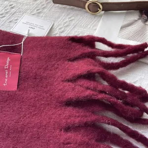 Close-up of deep red wool scarf showing thick knit texture and fringe details