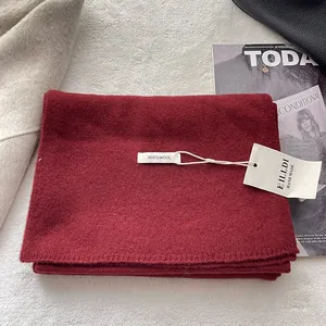 Detail shot of 100% wool scarf texture with product tags on a cozy plush background