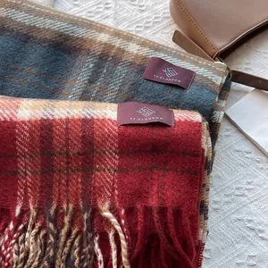 Close-up of retro plaid scarves with long tassels and branded woven label detailing
