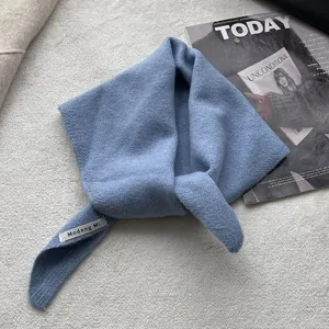 Détail de la texture d'un foulard triangle en laine tricotée bleue avec étiquette