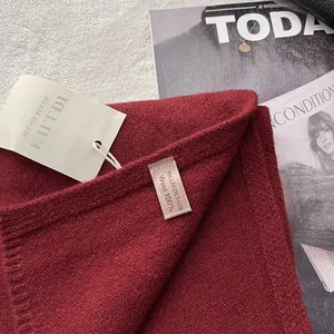 Macro shot of 100% pure wool knit texture with authentic wash label in wine red