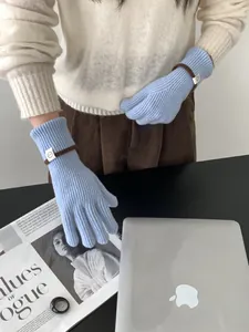 Détail de gants en tricot bleu clair avec texture côtelée et étiquette de poignet